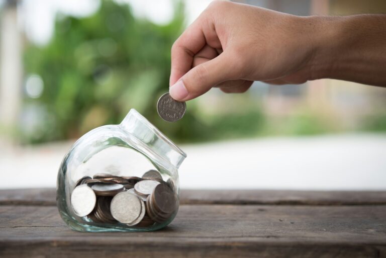 Man hands saving money into bottle for cash in future investment.