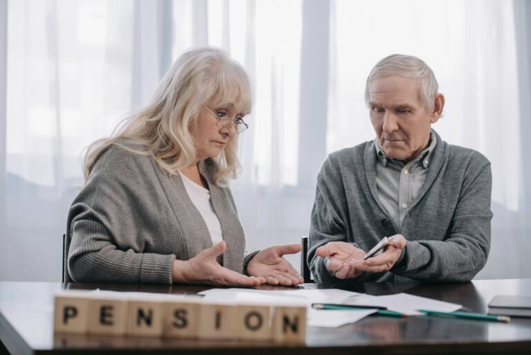 senior couple at table with word 'pension' made of wooden blocks on foreground