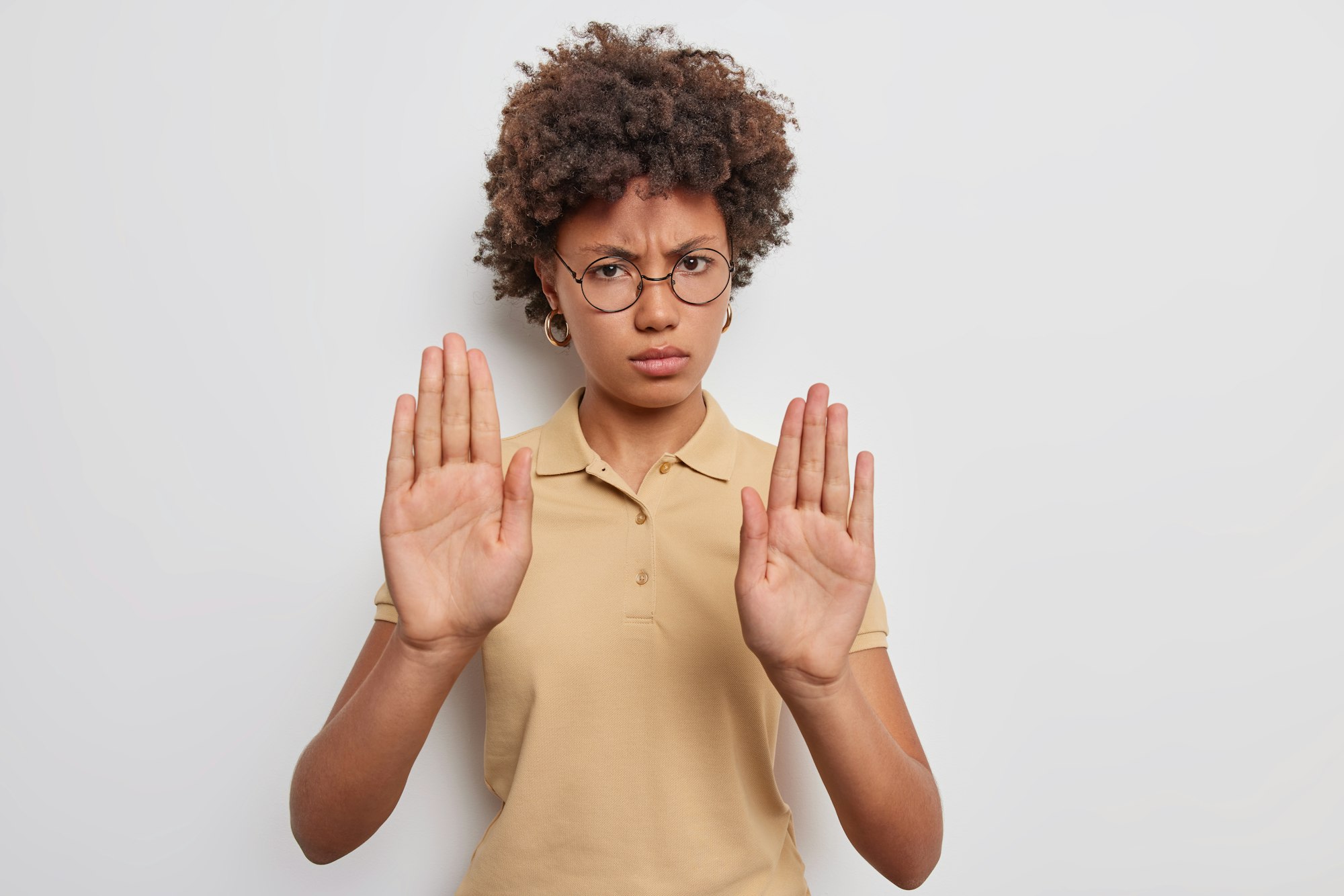 Stop this. Angry displeased Afro American woman extends palms and says no shows prohibition gesture